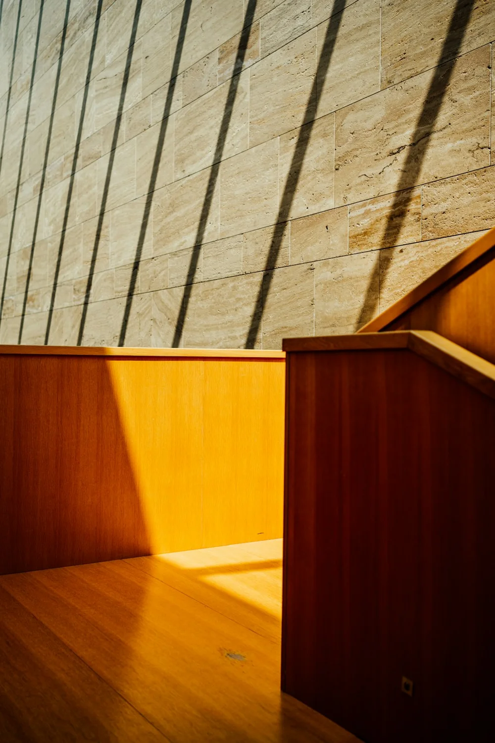 Luce naturale e ombre su una parete e una panca in legno